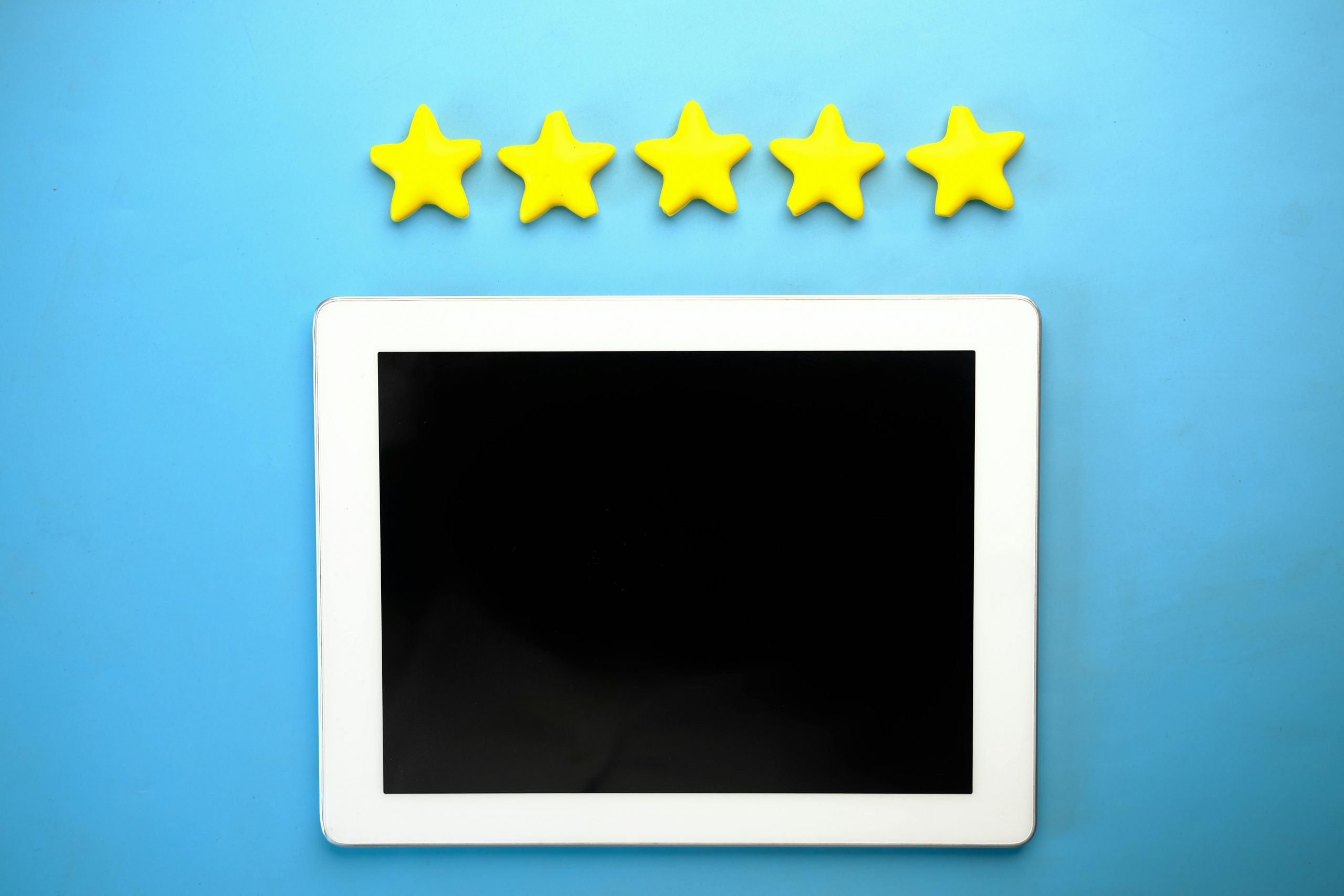 Tablet with five yellow stars on a blue background, ideal for rating concepts.